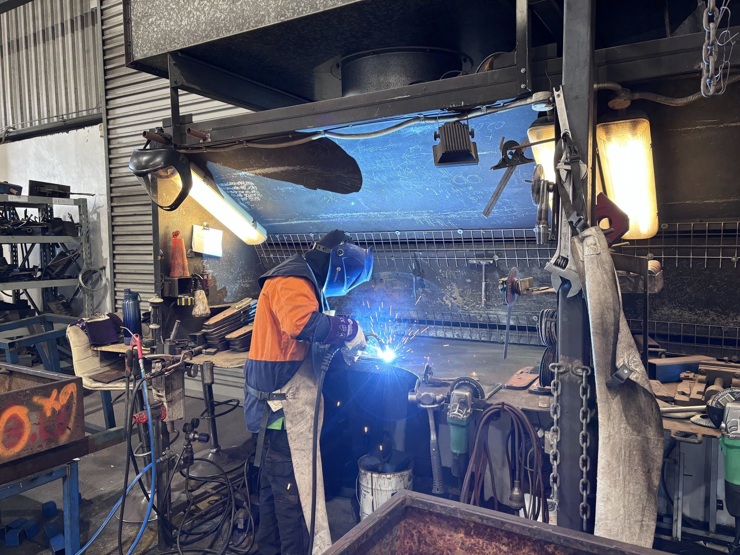 EdgeTech welder in full protective gear arc-welding a steel component