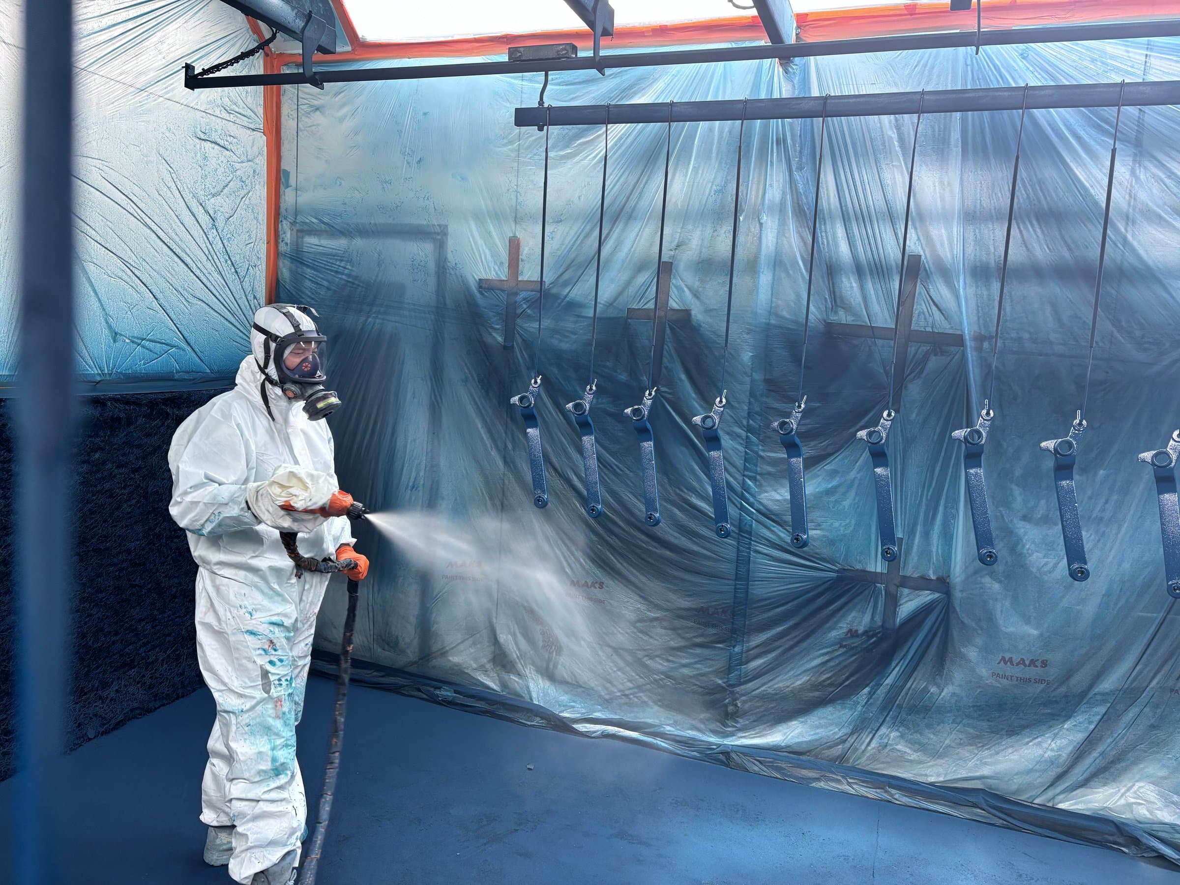 EdgeTech industrial painter in full respirator and coveralls spraying a coating